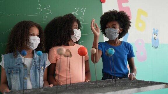 女孩们在教室里用口罩做关于太阳系的演讲