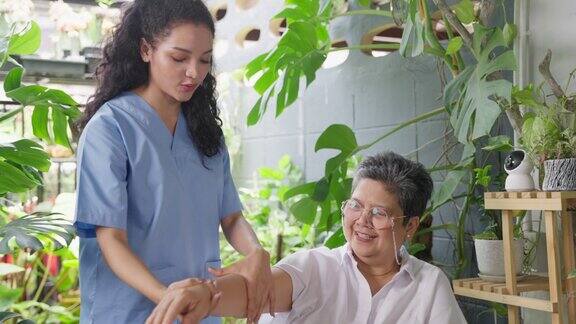 家庭保健东南亚老年人护理护士、理疗师在护理中帮助残疾老年病人做运动