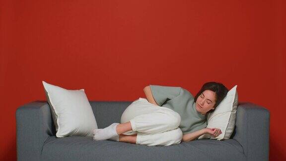 月经期疼痛综合症不健康的少女摸着肚子感觉肚子疼躺在沙发上