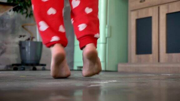女人的腿在家里的地板上赤脚跳舞穿着有趣的红色心形睡衣裤子