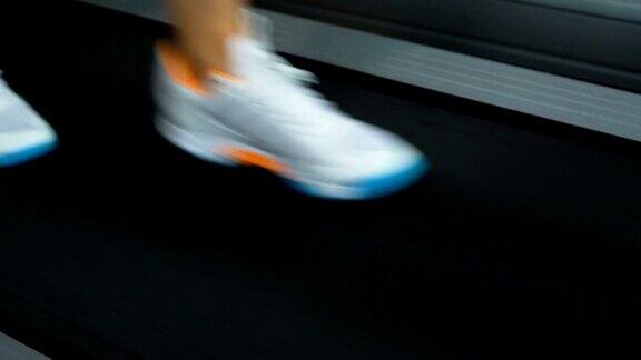 特写镜头的女人的腿跑在跑步机上在健身房