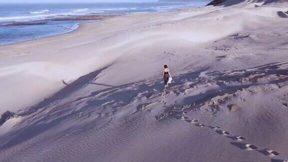 无人机飞过在沙滩沙丘上行走的女人