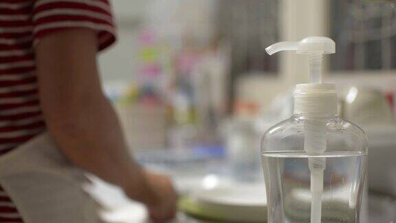 在COVID-19疫情期间使用酒精凝胶洗手的妇女妇女清洁厨房用具以防止病毒传播