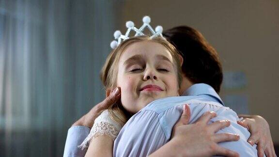 可爱的小女孩在公主皇冠裙拥抱父亲温柔的关系派对