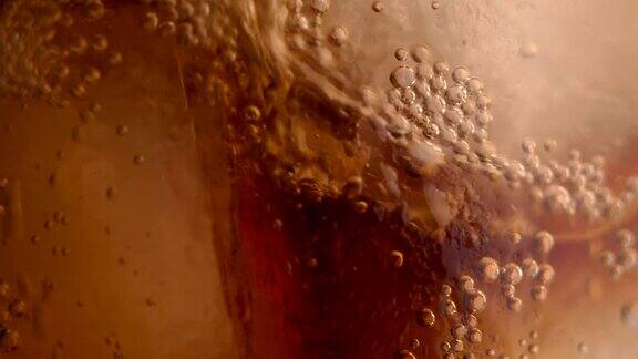 将冰凉的可乐苏打倒入加冰的玻璃杯中泡沫的苏打水4k慢镜头