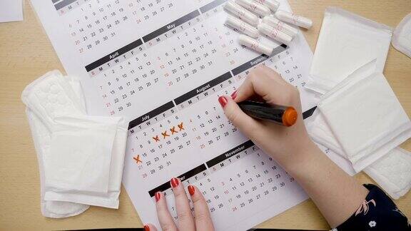 女孩用手计算她的排卵期用橙色记号笔在日历上标出日期同时问她为什么没有来月经
