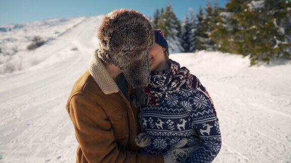 一个年轻人在雪山上用围巾温暖他的女朋友他们拥抱亲吻