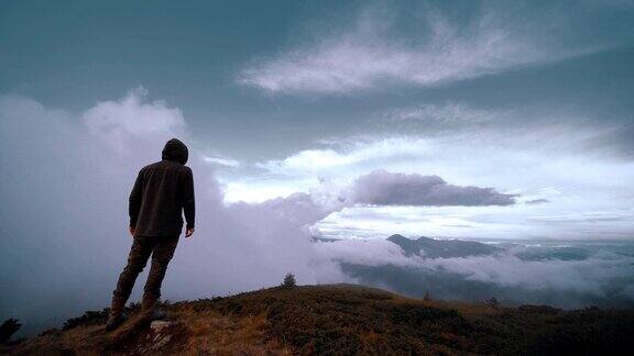 在云的背景上站在山上的男人慢动作