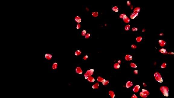 多汁的红色熟透的石榴粒在黑色的背景上跳跃