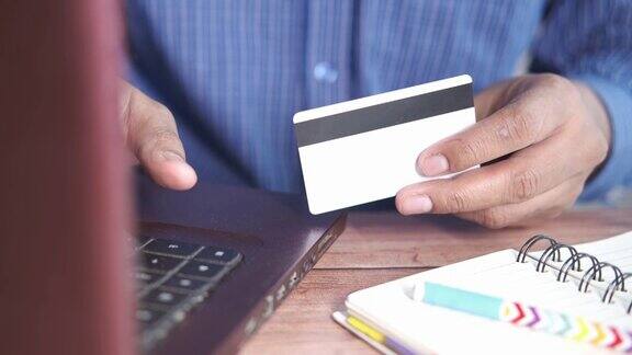 男人拿着信用卡用笔记本电脑在网上购物