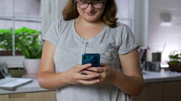 快乐的少女在现代厨房使用智能手机