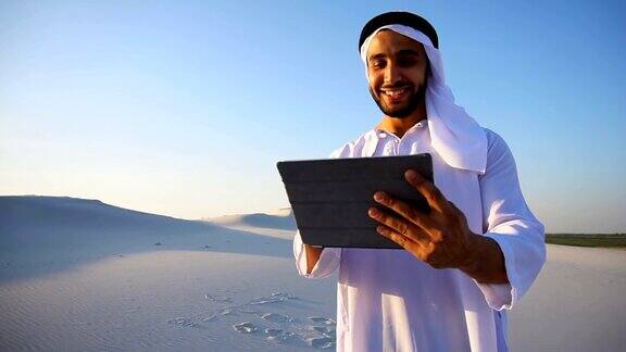 成功的阿拉伯商人手握平板站在夏夜的大沙漠中
