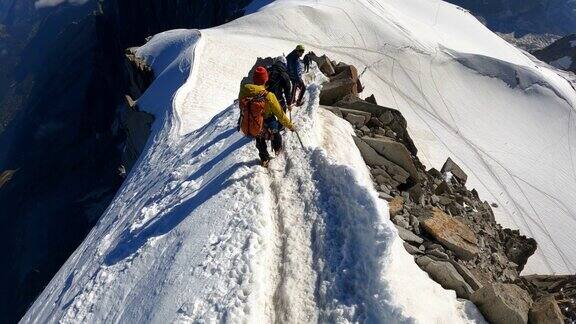 一队登山者正在攀登欧洲阿尔卑斯山的雪峰使用绳索和攀爬设备鸟瞰图
