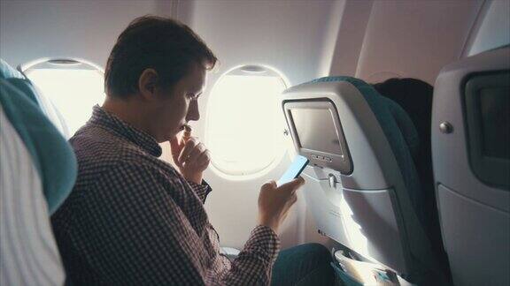 男子在飞机上浏览智能手机(慢镜头)