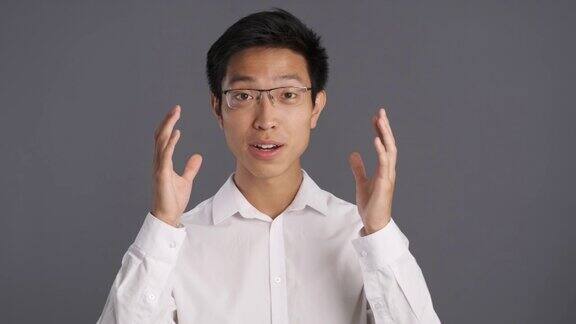 年轻的亚洲男子戴着眼镜惊讶地看着镜头哇表达式