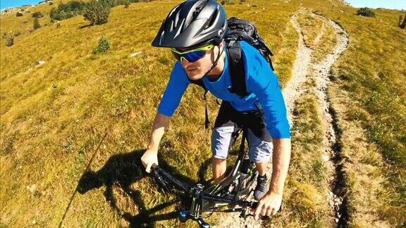在一个阳光明媚的日子里一名山地自行车手骑着自行车从山下穿过岩石山脉