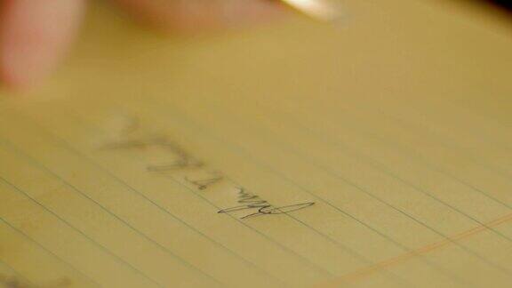 特写人物用钢笔在黄色笔记本上签名