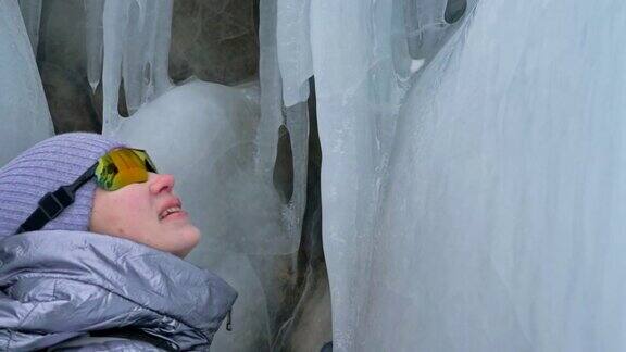 女人在贝加尔湖冰面上的旅行冬岛之旅女孩在冰岩石下行走游客看着美丽的冰洞极限跋涉和步行背包客在大自然中休憩