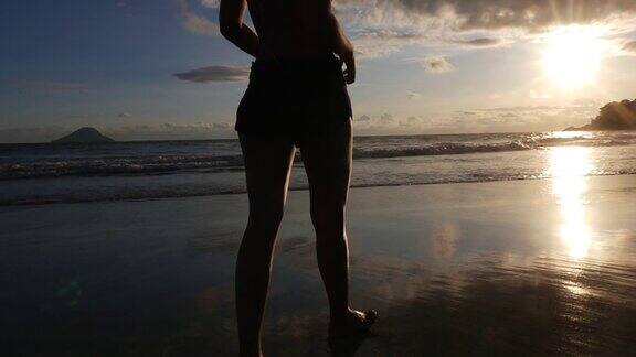 一个女人在巴西的海滩上走日落
