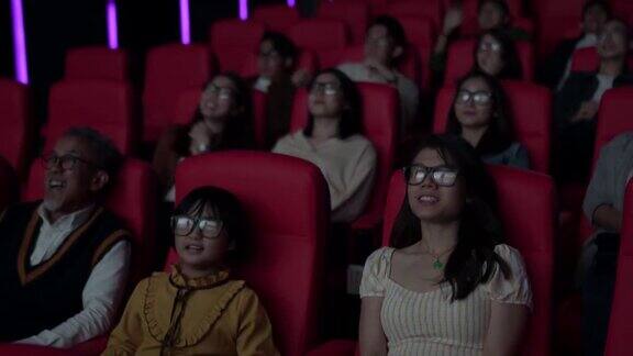一群亚洲观众带着3D眼镜在电影院观看3D电影
