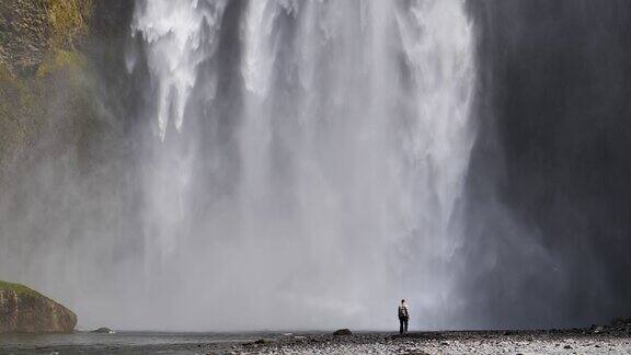 男子独自观看冰岛斯科加佛斯瀑布的慢镜头