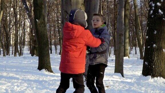 两个男孩在冬天的森林里打雪仗慢镜头