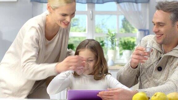 快乐的年轻父母和女儿玩在客厅里使用新技术