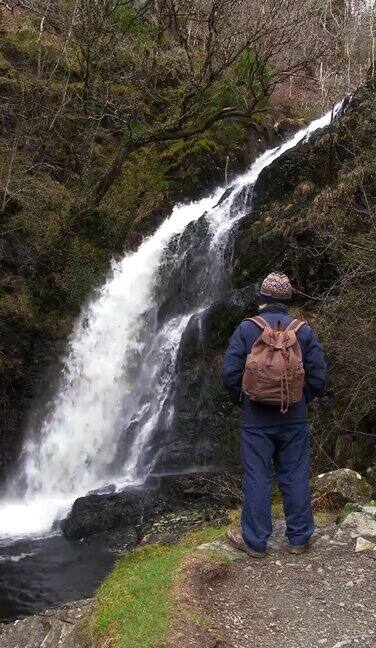 一个退休男子在春天的一天看瀑布