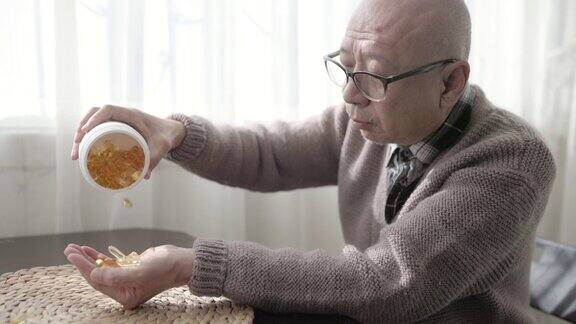 一位上了年纪的中国老人手里拿着一瓶药把胶囊倒出来用慢动作注射