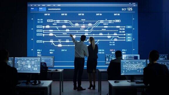 项目经理和计算机科学工程师在使用大屏幕显示基础设施信息图和数据时交谈电信公司系统控制和监控室