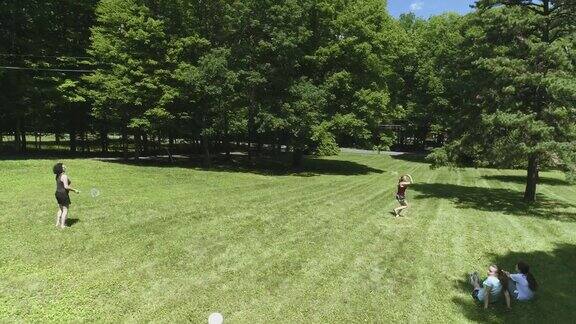 两个女人在草坪上打羽毛球她们的女儿在看比赛俯视图直接上方无人机视频
