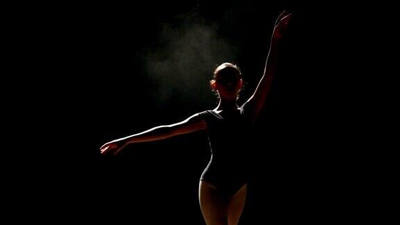 一个年轻的芭蕾舞者在黑色背景上摆姿势