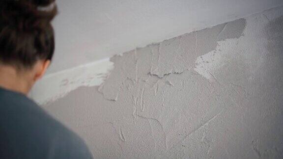 一位专业的修理工用抹刀在墙上抹灰泥