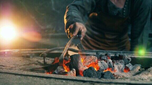 一个人在火炉里移动煤炭在熔炉里工作