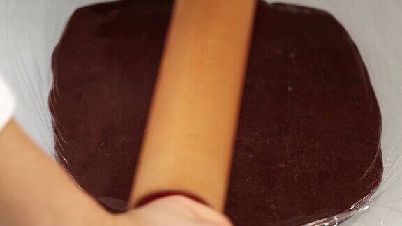 在桌上擀一块巧克力面团来做饼干