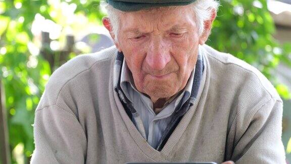 白发苍苍的老爷爷看着智能手机屏幕老人的脸凑近了