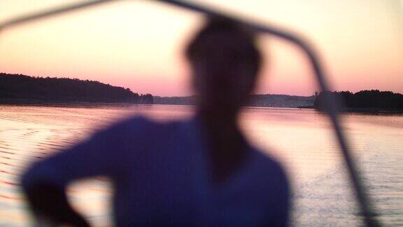浪漫的湖上日落从船上看风景的年轻人