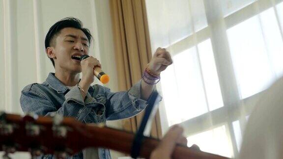 年轻的亚洲歌手用吉他伴奏唱歌