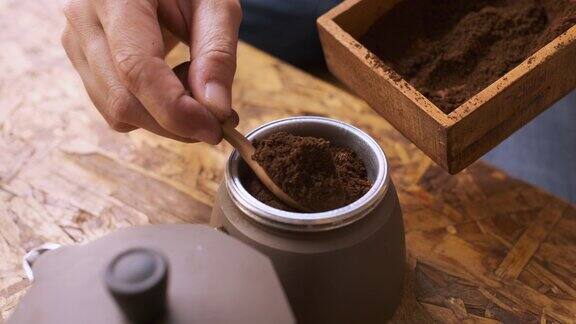 用手将新鲜磨碎的咖啡粉放入摩卡壶的咖啡片中