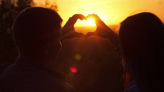 日落时分一对浪漫的情侣在手上画了一个心形