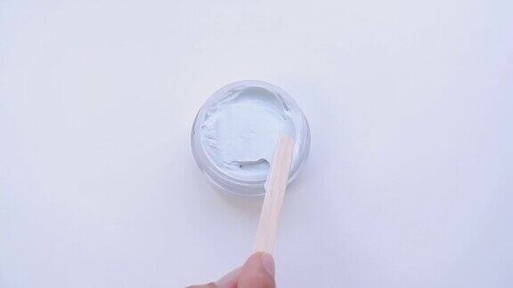 搅拌奶油、面膜的木棒装在白色背景的罐子里的温和的化妆品化妆品质地身体护理