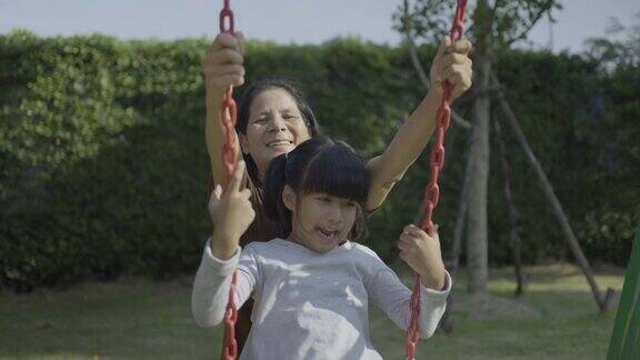 母亲和女儿一起在公园里荡秋千的慢镜头