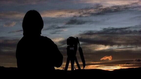 摄影师带着相机在三脚架上等待日落