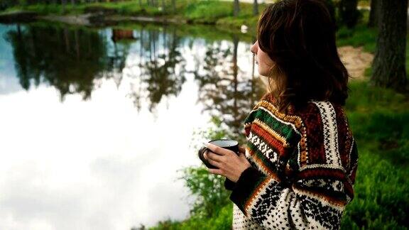在挪威森林湖边喝茶的女人
