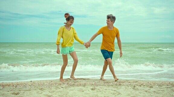 夏天一对年轻的热恋情侣站在海滩上拥抱亲吻人们走向镜头
