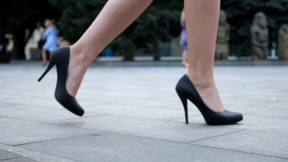穿着高跟鞋的年轻女商人的双脚在城市中穿行女人们穿着高跟鞋走在城市的街道上女孩走着去上班慢动作近景低角度视图