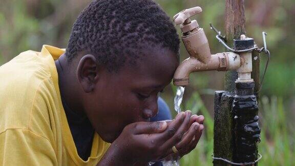 一个非洲黑人小男孩坐在公共水点喝水的特写水危机贫困气候变化全球变暖干旱
