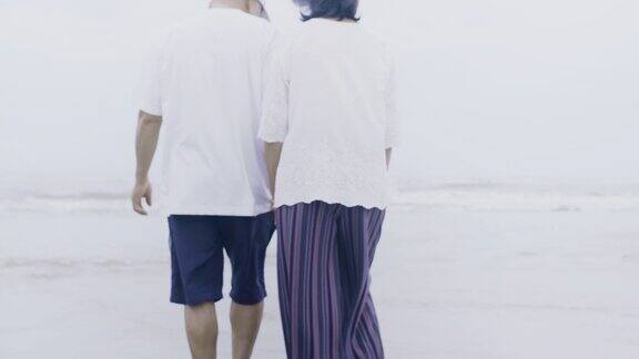 亚洲老夫妇一起在海边散步在周末假期的背景老年人幸福生活