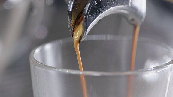 一个专业的咖啡机将咖啡从门滤嘴倒入两个杯子