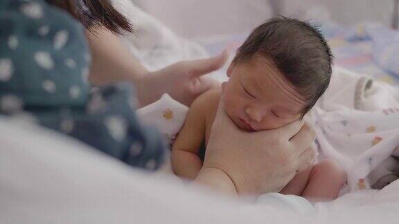 亚洲妈妈在给宝宝喂奶后用奶瓶喂奶帮助宝宝消化食物